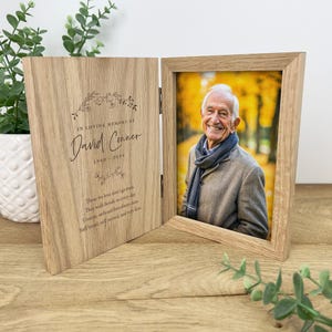 May include: A wooden photo frame with a hinged front panel. The front panel has a photo of an older man smiling. The back panel has an inscription that reads "In loving memory of David Conner 1940-2024" and a poem about remembering loved ones.