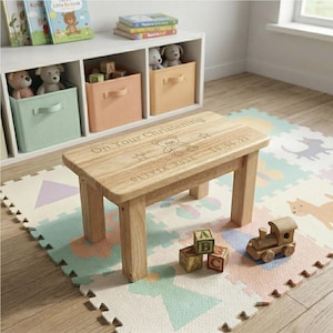 May include: A small, light-coloured wooden table with the inscription "On Your Christening" and a teddy bear design. The table is surrounded by a colourful play mat, wooden blocks, and a toy train. The table measures approximately 46 cm long.