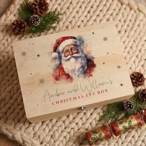 Könnte beinhalten: Eine rechteckige Holzbox mit einer Aquarellillustration des Weihnachtsmanns mit weißem Bart und roter Mütze. Der Text lautet Amber and William's CHRISTMAS EVE BOX. Die Box ist mit kleinen Sternen und Schneeflocken auf dem Holz bedruckt.