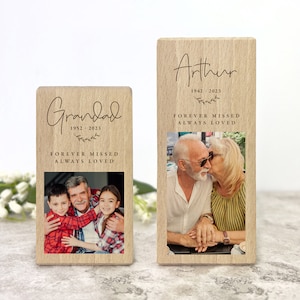 Pode incluir: Dois porta-retratos de madeira com acabamento marrom claro. Os porta-retratos são gravados com os nomes "Grandad" e "Arthur" e as datas "1952-2023" e "1942-2023". Os porta-retratos também incluem o texto "Forever Missed Always Loved". Cada porta-retrato tem uma foto de uma família.