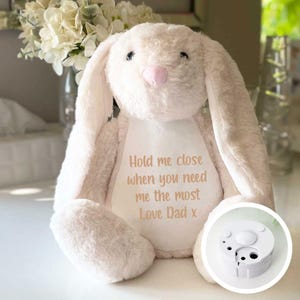 May include: A white plush bunny with long ears and a pink nose. The bunny has a white patch on its chest with the text "Hold me close when you need me the most Love Dad x".