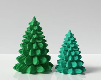 Puede incluir: Dos árboles de Navidad impresos en 3D, uno más grande que el otro, están hechos de plástico verde brillante. Los árboles están sobre una superficie blanca.