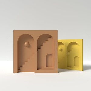 Pode incluir: Duas formas geométricas impressas em 3D com aberturas arqueadas e escadas. A forma maior é marrom e a menor é amarela.