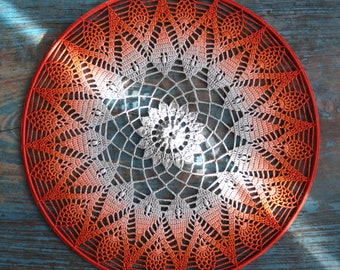 May include: A large, round, crocheted doily with a white center and an ombre effect that transitions from white to orange. The doily is made with a delicate, lacy stitch and has a scalloped edge.