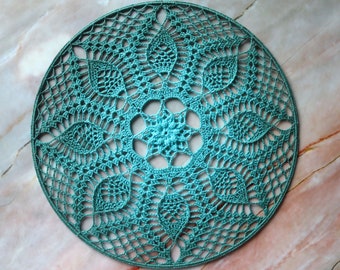 May include: A teal crocheted doily with a circular design featuring intricate floral patterns.