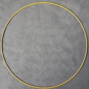May include: A thin, yellow, circular hoop against a grey background. The hoop is a complete circle, with a consistent width and a smooth, matte finish. The image is a top-down view, with the hoop centered.