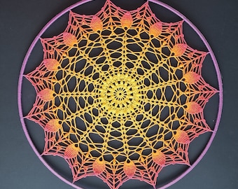 May include: A circular crocheted mandala with a pink and yellow color gradient. The mandala is made of delicate, intricate stitches and has a floral design.
