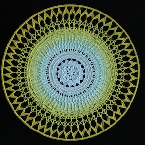 May include: A crocheted mandala with a yellow and blue ombre design. The mandala has a central flower design and is surrounded by a series of concentric circles.