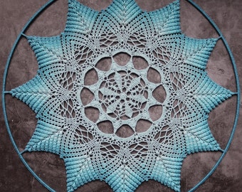 May include: A large, blue crocheted doily with a starburst design. The doily is hanging on a circular metal frame.