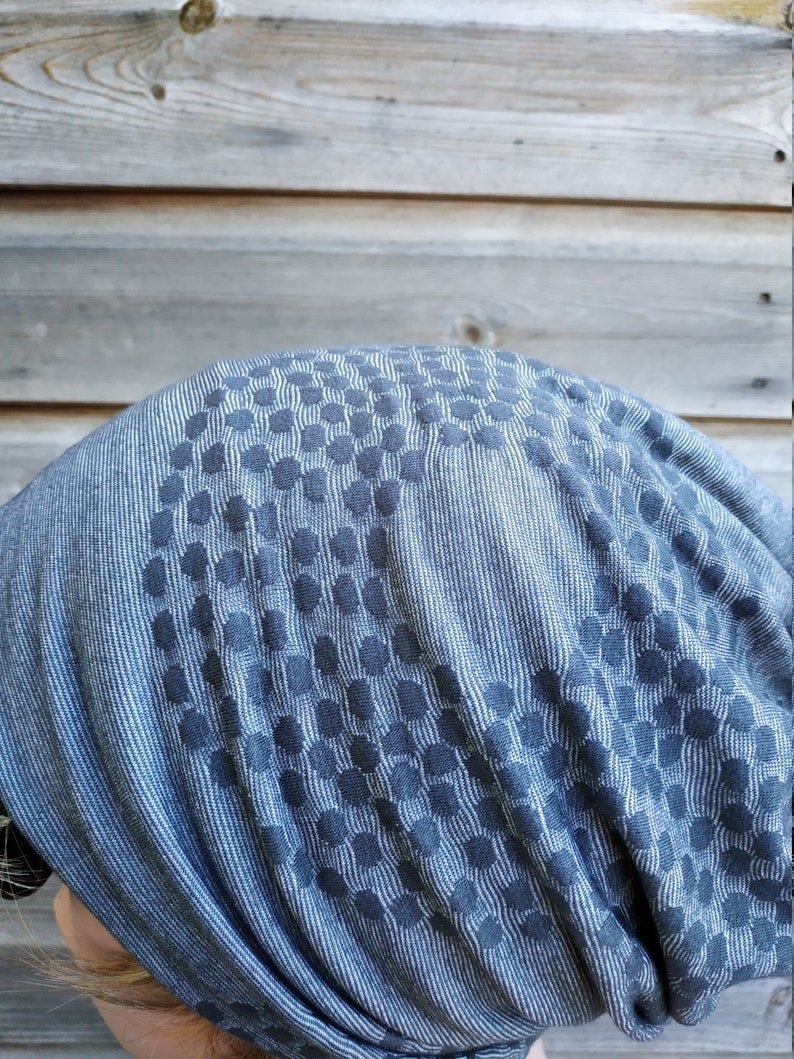 Pu&ograve; includere: Un berretto a maglia grigio e bianco con motivo. Il berretto &egrave; realizzato in un tessuto morbido ed elastico e presenta un design geometrico.