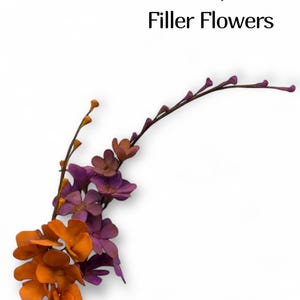 May include: A floral arrangement of artificial filler flowers in shades of orange and purple. The flowers are arranged on thin, brown stems against a white background. The text "Sha'SweetsArts" and "Filler Flowers" is at the top.