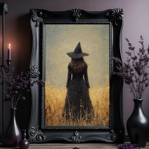 Może przedstawiać: Oprawione dzieło sztuki przedstawia postać w czarnej sukni i kapeluszu czarownicy na polu. Fioletowe kwiaty w wazonach i świecznik ze świecami znajdują się na drewnianej powierzchni. Tematem jest gotyk.