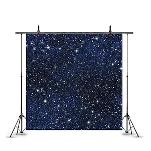 May include: A square photography backdrop featuring a deep navy blue night sky filled with a dense pattern of white stars of varying sizes. The fabric is suspended from a black metal stand with two vertical poles and a horizontal crossbar.