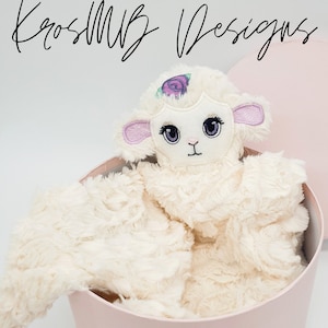 Könnte beinhalten: Ein cremefarbenes Plüschlamm-Spielzeug mit gestickten Gesichtszügen und einer lila Blume auf dem Kopf, eingebettet in einer rosa herzförmigen Box. Die Box ist mit einem rosa Band gebunden.