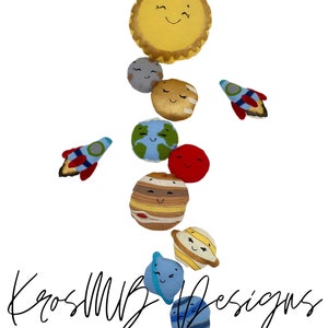 May include: A set of plush toys depicting the sun and planets in our solar system. The sun is yellow with a smiling face, and the planets are various colors with smiling faces. There are also two small red and blue rockets.