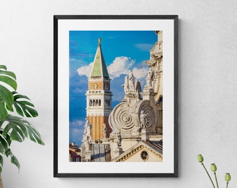 Puede incluir: Una fotografía enmarcada de una torre alta, naranja y blanca con un techo verde, contra un cielo azul con nubes blancas. La torre es parte de un edificio más grande con intrincados trabajos en piedra y estatuas.