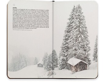 May include: An open book with a snowy winter scene on the right page. The scene features a small wooden cabin nestled among tall, snow-covered pine trees. The left page contains text in Italian about a Christmas legend.