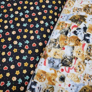 May include: Two fabric swatches, one black with a repeating pattern of gingerbread cookies, stars, and fish, and the other white with a repeating pattern of kittens with different colored fur.