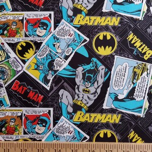 Puede incluir: Una tela negra y azul con un patr&oacute;n repetido de vi&ntilde;etas de c&oacute;mics con Batman. Las vi&ntilde;etas est&aacute;n rasgadas y desgarradas, creando un aspecto desgastado. La tela presenta las palabras "BATMAN" en letras amarillas y un s&iacute;mbolo de murci&eacute;lago amarillo.