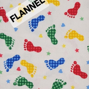 May include: White flannel fabric with a repeating pattern of colorful footprints in red, blue, green, and yellow. The fabric also features small hearts and stars. The word "FLANNEL" is printed on a white label.