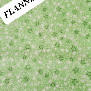 May include: Green flannel fabric with a white star pattern. The fabric has a label that says "FLANNEL".