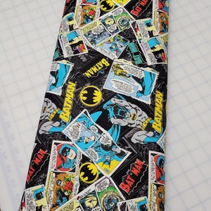 Puede incluir: Tela negra con un patr&oacute;n repetido de vi&ntilde;etas de c&oacute;mics con Batman. Las vi&ntilde;etas son de varios colores, incluyendo rojo, amarillo, azul y verde. El texto "BATMAN" aparece varias veces en la tela.