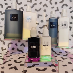 May include: Five bottles of ink, two black, two white, and one clear. The bottles are arranged on two clear acrylic shelves. The bottles are labelled "BLACK" and "WHITE".