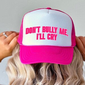 Könnte beinhalten: Rosafarbener Trucker-Hut mit weißem Netzrücken. Der Hut trägt den Text "Don't Bully Me, I'll Cry" in rosa Buchstaben.
