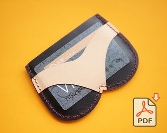 May include: A black leather card holder with a gold leather insert. The card holder has a red stitch around the edges and a credit card is visible inside.