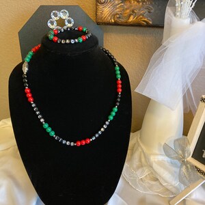 May include: Black Lives Matter necklace and bracelet set with black, red, and green beads. The beads are strung on black cord and have the words "Black Lives Matter" spelled out on them.