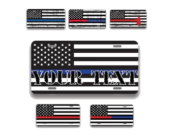 May include: License plates with American flag designs. The plates feature the stars and stripes, with variations including blue, red, and white lines. One plate has the text "YOUR TEXT" in a distressed font.