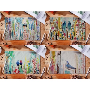 May include: Set of four colorful placemats featuring watercolor-style bird illustrations. Each placemat has a different design with birds in various poses and colors against a background of abstract floral patterns.
