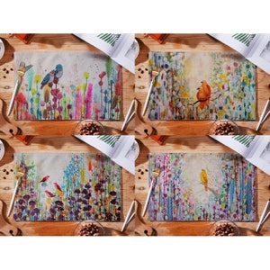 May include: Set of four colorful placemats featuring watercolor-style floral designs with birds. Each placemat has a different bird and floral arrangement. The placemats are made of linen and are perfect for adding a touch of nature to your dining table.