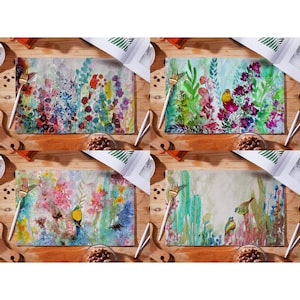 May include: Set of four colorful floral and bird design placemats. Each placemat features a different watercolor design with a variety of flowers, leaves, and birds in shades of pink, blue, green, yellow, and orange.