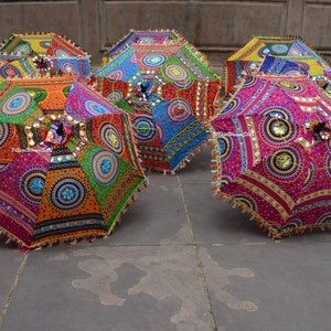 Puede incluir: Un grupo de seis paraguas coloridos y estampados con flecos. Los paraguas están hechos de tela y tienen una variedad de diseños circulares en tonos de rosa, azul, verde, naranja y amarillo.