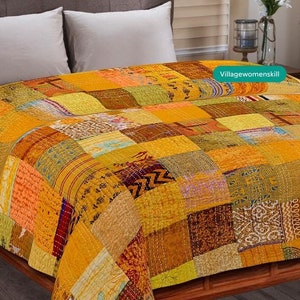 May include: A yellow, orange, and brown patchwork quilt with a quilted design. The quilt is made of various fabrics and has a vintage look. The quilt is on a bed with white pillows.