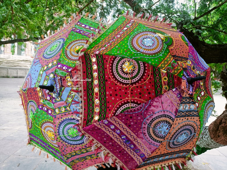 Puede incluir: Una sombrilla colorida y multi-patrones con un borde de flecos. La sombrilla est&aacute; hecha de tela con c&iacute;rculos bordados y detalles de espejo.