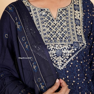 May include: A navy blue kurta with a floral print and gold embroidery. The kurta has a V-neckline and is adorned with sequins and mirror work. The kurta is paired with a matching dupatta.