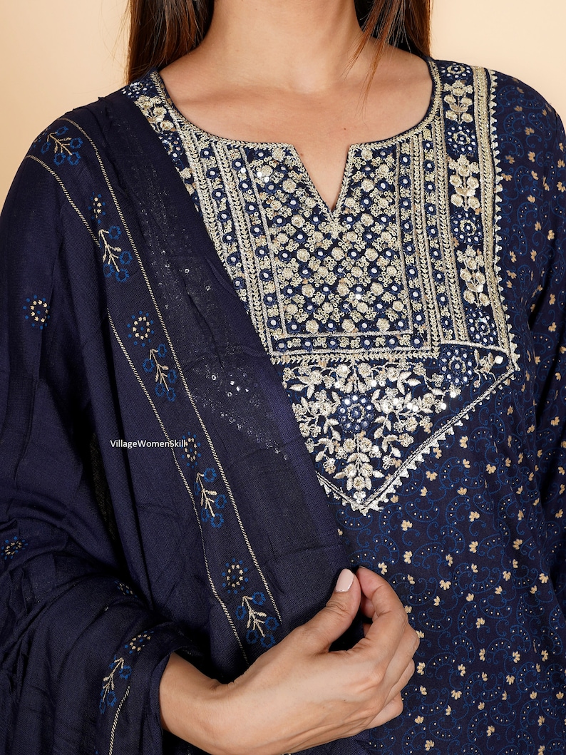 May include: A navy blue kurta with a floral print and gold embroidery. The kurta has a V-neckline and is adorned with sequins and mirror work. The kurta is paired with a matching dupatta.