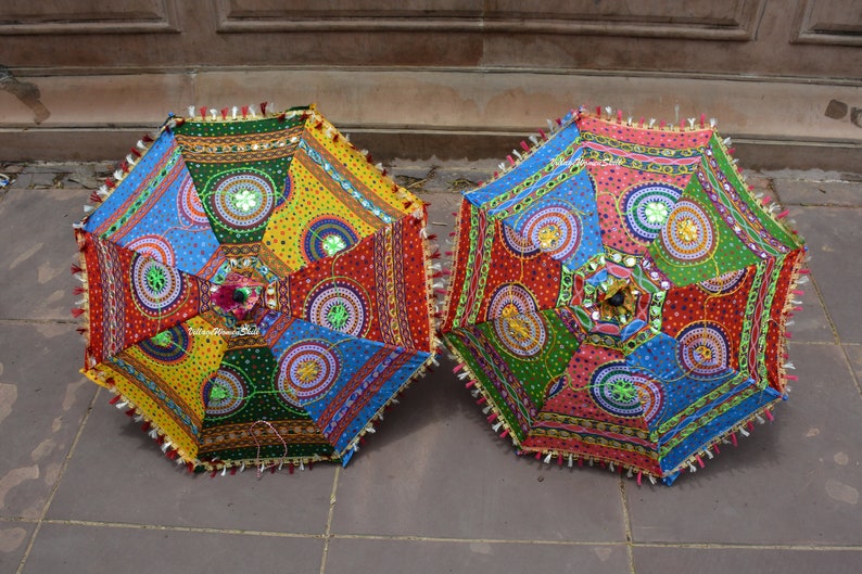 Puede incluir: Dos paraguas coloridos con intrincados patrones y adornos. Los paraguas est&aacute;n hechos de tela y tienen una variedad de colores, incluyendo rojo, azul, verde, amarillo y rosa. Los paraguas est&aacute;n decorados con lentejuelas y cuentas.