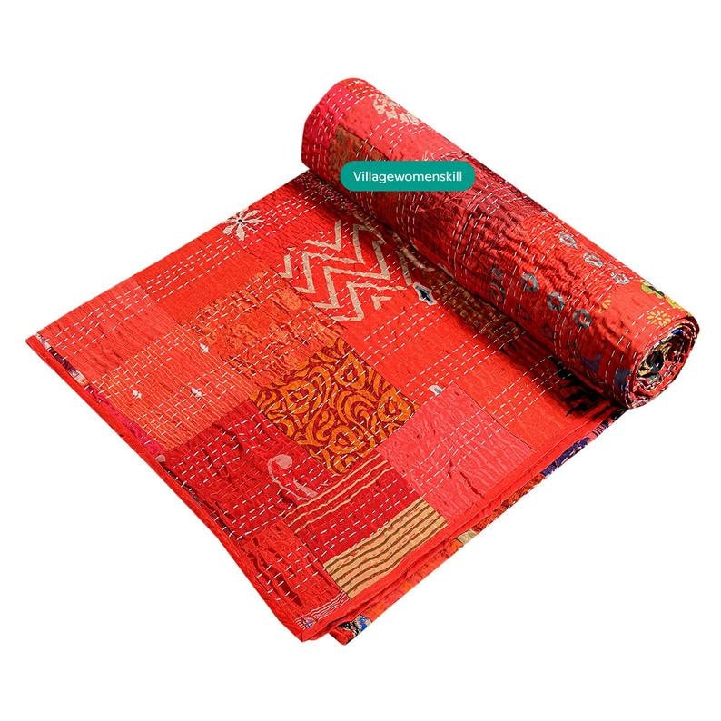 Pu&ograve; includere: Una trapunta kantha rossa con un design a patchwork che presenta vari motivi e colori. La trapunta &egrave; arrotolata su un lato, rivelando le intricate cuciture.