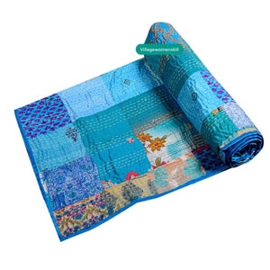 Pu&ograve; includere: Una trapunta patchwork blu e bianca con un motivo floreale. La trapunta &egrave; arrotolata e ha un'etichetta che dice "Villagewomenskill".