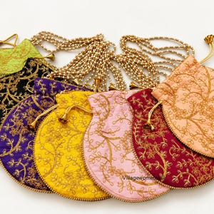 May include: A collection of seven round drawstring pouches in lime green, black, purple, yellow, light pink, dark red, and peach. Each pouch features gold floral embroidery, a beaded pearl handle, and gold-toned drawstring cords.