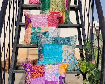 May include: Five colorful patchwork pillow covers with different patterns and colors, including pink, green, blue, and purple. The pillow covers are arranged on a black metal staircase.