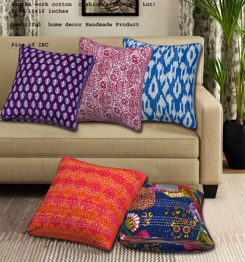 May include: Five colorful square throw pillows with different patterns on a beige couch. The pillows are made of cotton and have a kantha stitch design. The pillows are 16 inches by 16 inches.