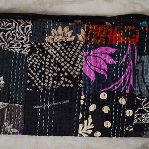May include: Black kantha quilt with a patchwork design featuring floral and geometric patterns. The quilt is hand-stitched and has a "Village Women Skill" label.