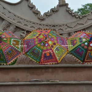 May include: Three colourful umbrellas with intricate embroidery and mirror embellishments. The umbrellas are decorated with floral patterns and elephant motifs.
