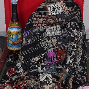 Puede incluir: Colcha kantha negra con un diseño de patchwork que presenta varios patrones florales y geométricos. La colcha está cosida a mano con detalles intrincados y tiene una estética vintage.