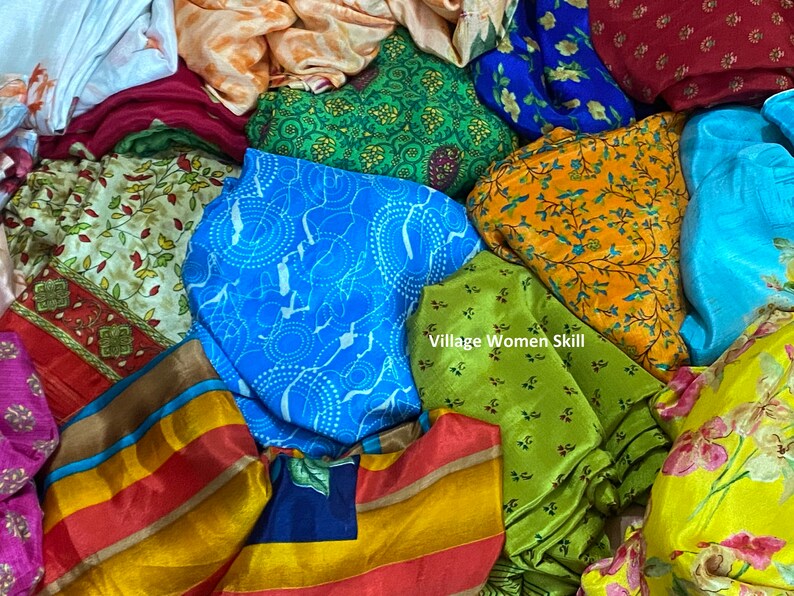 May include: A pile of colorful fabric scraps with various patterns, including floral, geometric, and striped designs. The fabrics are made of silk and are arranged in a random order. The text "Village Women Skill" is visible in the center of the image.
