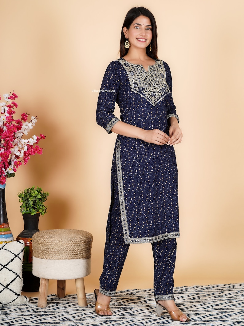 May include: A navy blue kurta and palazzo set with gold embroidery and a small white floral print. The set features a V-neckline and three-quarter sleeves.